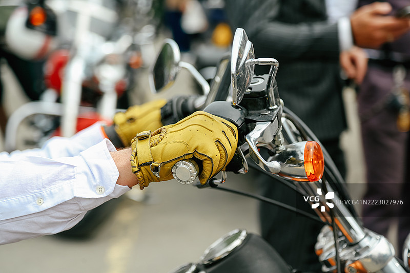 男性的手戴着黄色复古皮手套，握住摩托车的把手图片素材