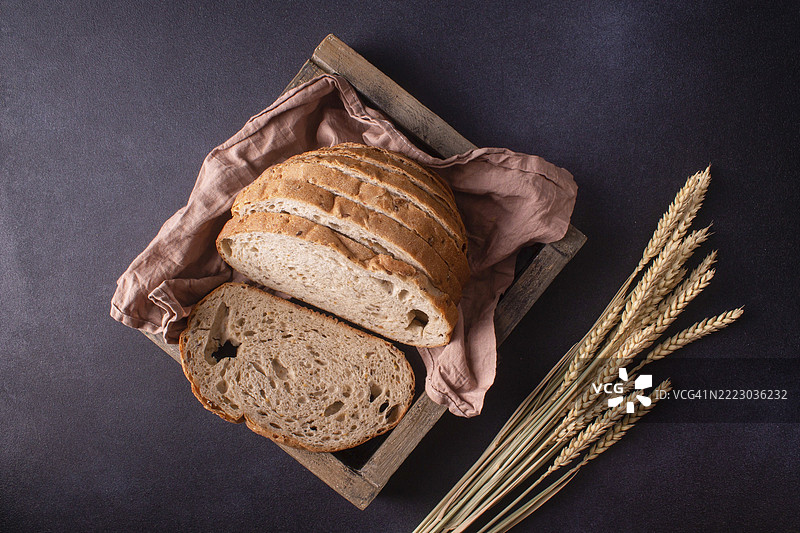 方形木箱中的切片全麦面包与麦穗，俯视图图片素材