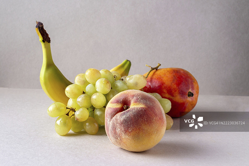 桌子上有香蕉、青葡萄、芒果和桃子。图片素材