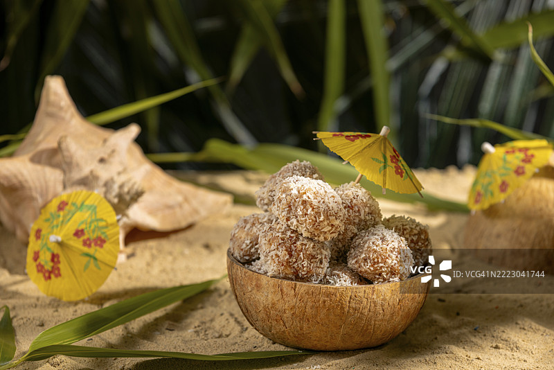 椰子，沙滩上装满甜点的碗，装饰着黄色伞。图片素材