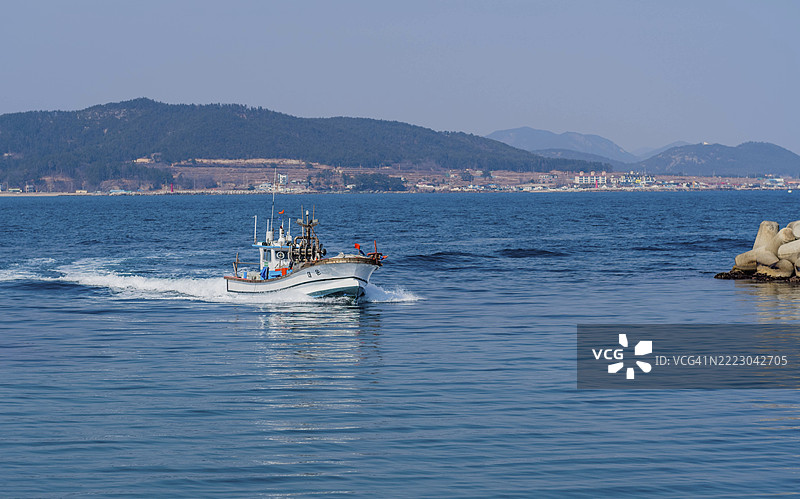 韩国丽水，2023年2月23日：渔船在朦胧的天空下驶入港口图片素材
