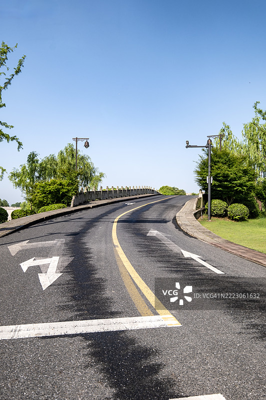 轻微弯曲的道路，带有车道标记和花园照明图片素材
