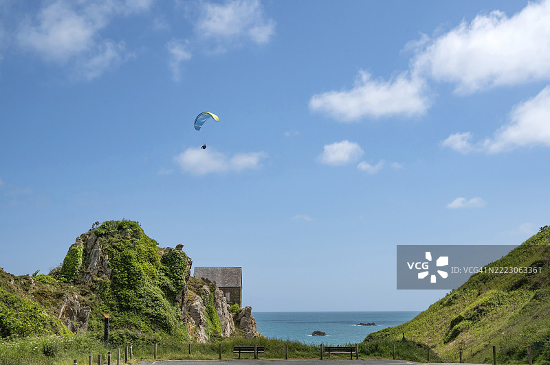 布列塔尼花岗岩石屋上方的滑翔伞，屋顶为石板瓦，位于圣布里厄湾的圣阿尔莫尔省普卢哈附近的科沙海湾，博纳巴特海滩上方的“海岸之路”主题公路的海岸小径上，布列塔尼，图片素材