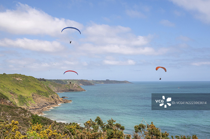 在法国布列塔尼的北部悬崖上空滑翔，背景是GR 34长途徒步旅行路线和标记的旅游路线“悬崖之路”，位于普卢哈，圣布里厄湾，阿摩尔海岸，布列塔尼，欧洲。图片素材