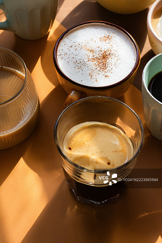 不同呈现方式的早晨咖啡，背景为橙色和陶土色。各种咖啡饮品。图片素材
