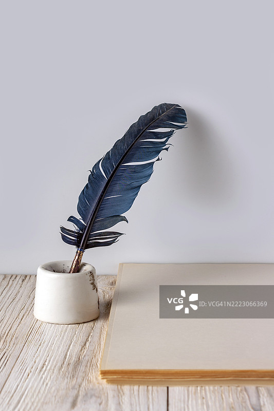 羽毛、墨水瓶和一叠纸张放在白色木质背景上，留有空白空间图片素材