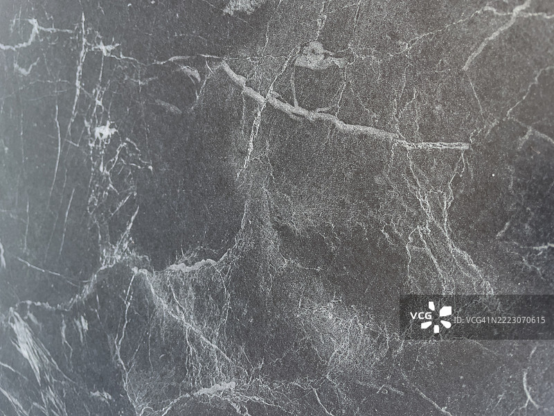 一张黑白照片，展示了一面有很多裂缝和洞的石墙。图片素材