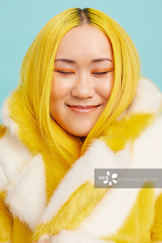 微笑的年轻女性，金色头发，穿着毛皮外套图片素材