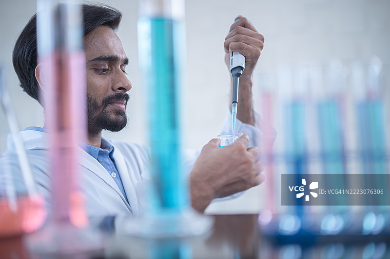 科学家在实验室进行实验，使用移液管和五颜六色的试管，展示现代化学中的科学研究与创新。图片素材