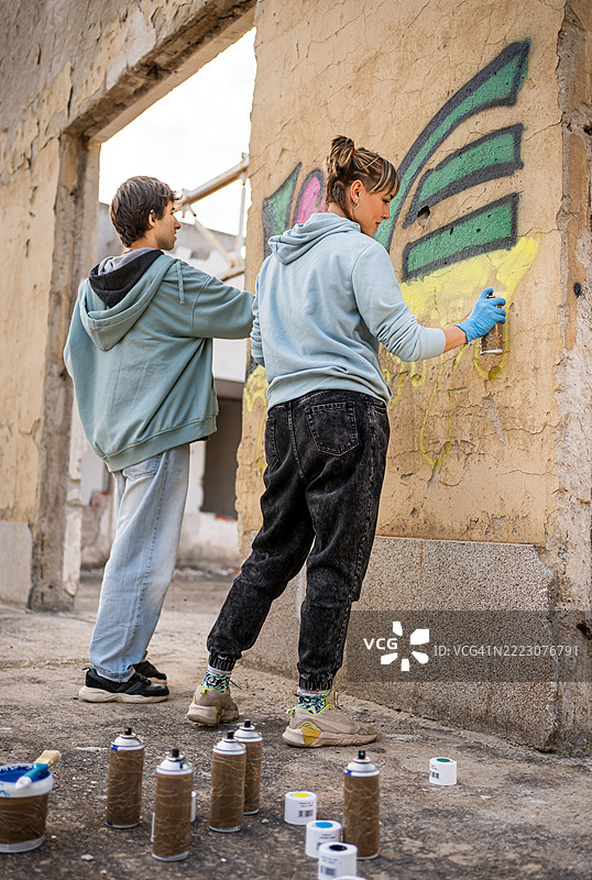 年轻艺术家在废弃建筑的墙壁上涂鸦图片素材