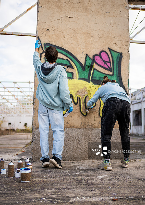 两个年轻的涂鸦艺术家在废弃建筑的墙上作画图片素材