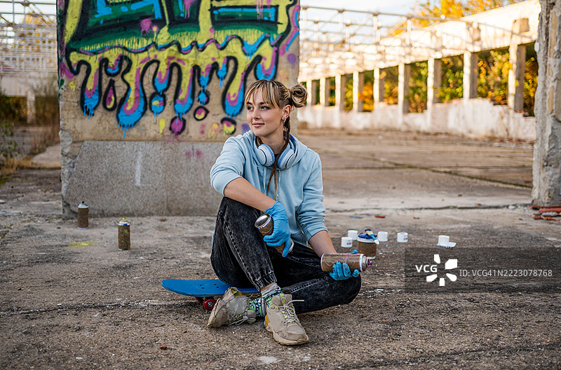 年轻女性涂鸦艺术家在滑板上休息图片素材