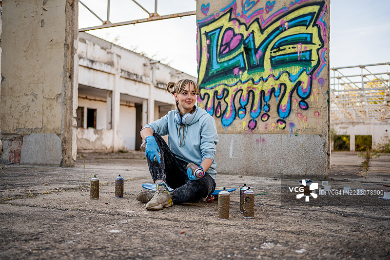 年轻女性涂鸦艺术家在废弃建筑中休息图片素材