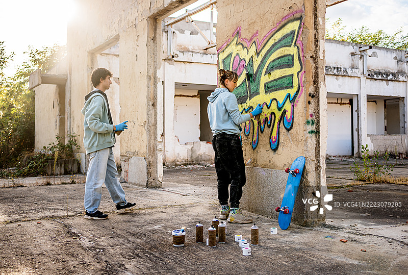 年轻艺术家在废弃建筑的墙上涂鸦图片素材