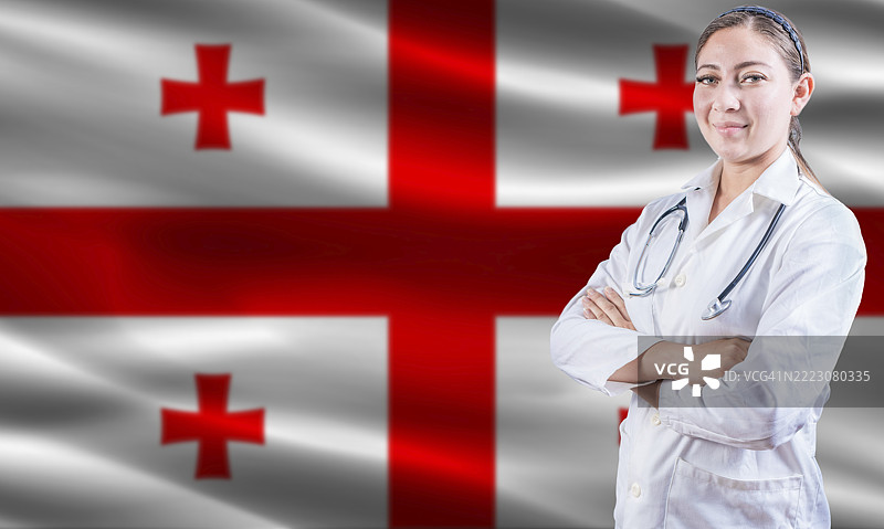 佐治亚州州旗上的女医生。双臂交叉的女医生站在佐治亚州州旗上。佐治亚州健康与关怀概念。图片素材