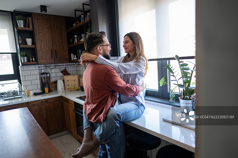 年轻情侣在现代厨房中相拥图片素材