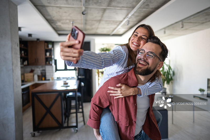 快乐的情侣在现代公寓里自拍图片素材