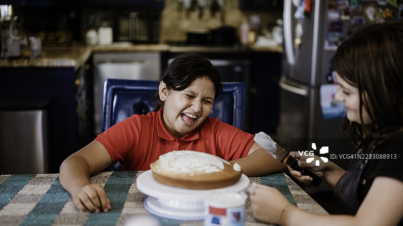 两个不同种族的小女孩朋友在家一起给自制蛋糕涂霜和装饰。图片素材