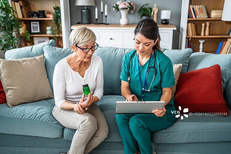 护士使用数字平板向老年女性展示药物信息图片素材