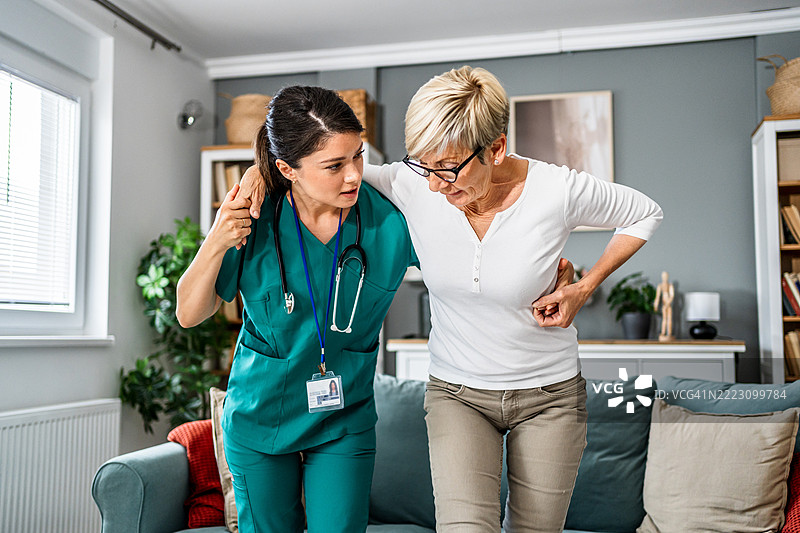 护士在家中帮助老年女性从沙发上起身图片素材