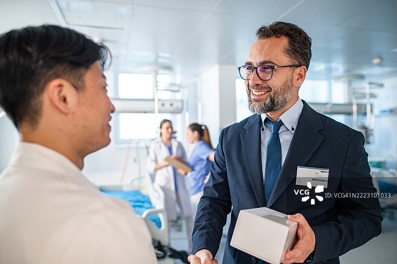 制药销售代表与年轻医生握手，介绍新药物。图片素材