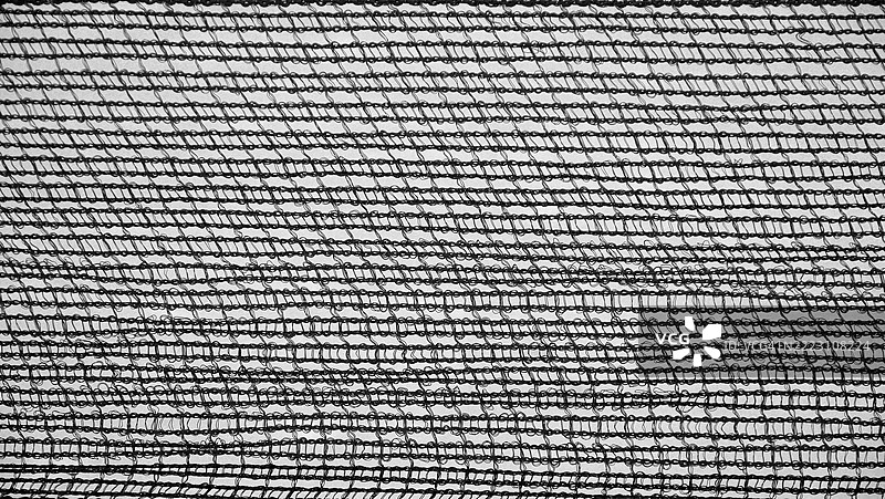 红色塑料网的特写,背景是蓝天。阳光。黑白。粗糙的纹理。法国,上萨瓦省,埃维昂-莱-班。图片素材