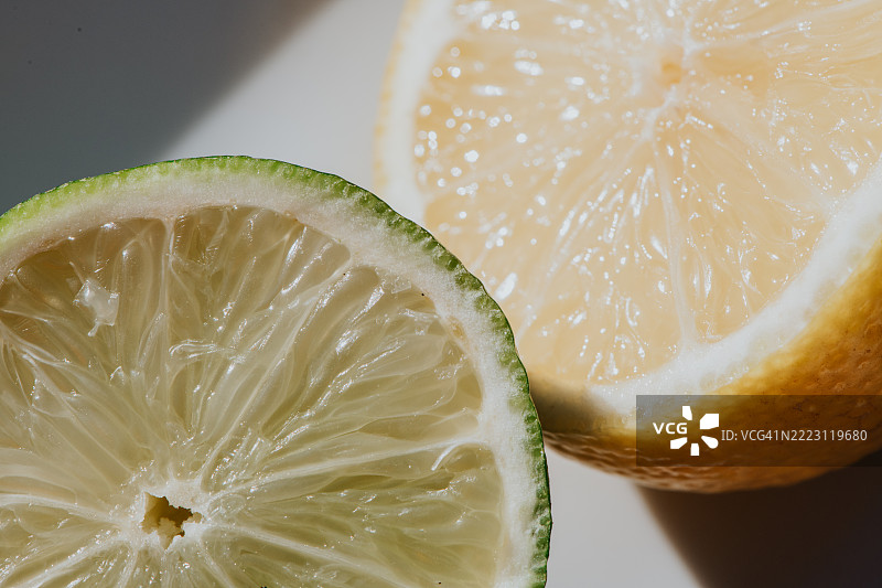 Freshly cut lemon and lime halves showcasing vibrant colours and textures on a clean surface图片素材