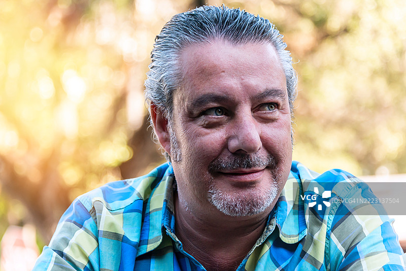 微笑的西班牙裔成熟男性摆姿势仰望天空图片素材