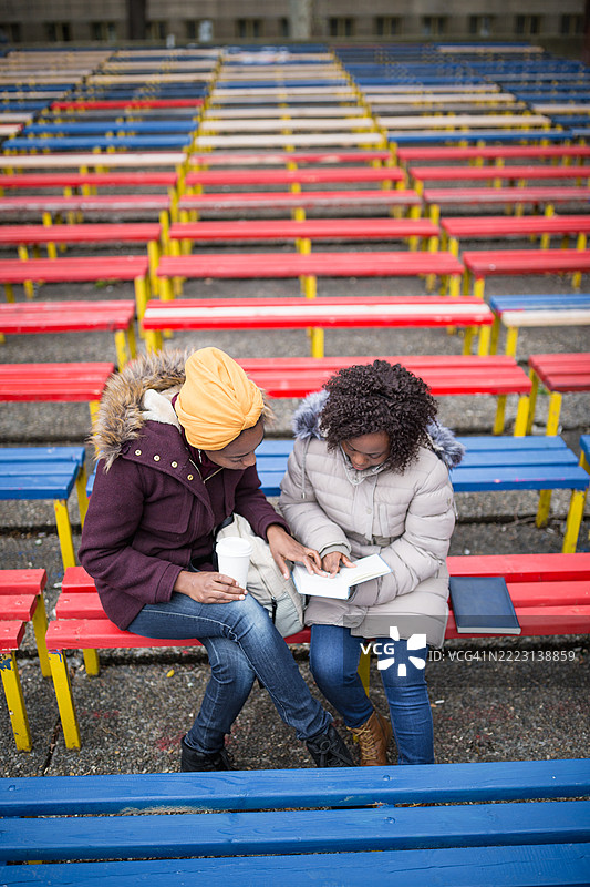 女性在晨光中共享早餐，坐在色彩斑斓的长椅上图片素材