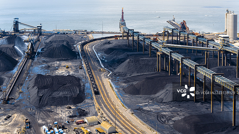 在弗吉尼亚州纽波特纽斯港的煤炭码头储存和处理煤炭。工业区湿润的煤堆。鸟瞰图。图片素材