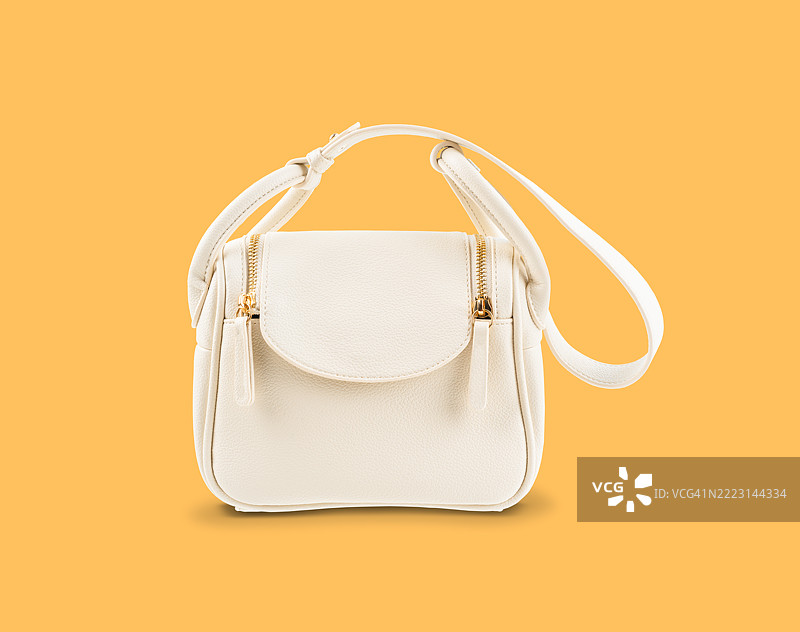 白色皮革女包，孤立在黄色背景上。图片素材
