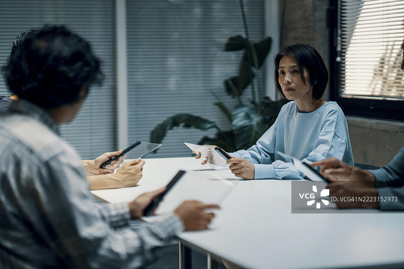 成熟的女性在办公室会议中使用先进技术。图片素材