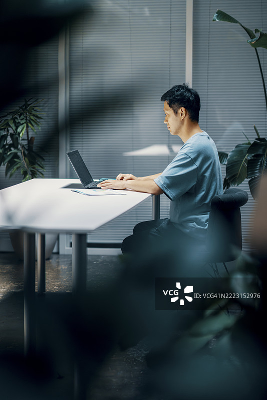 成年男性坐在桌子旁使用笔记本电脑图片素材