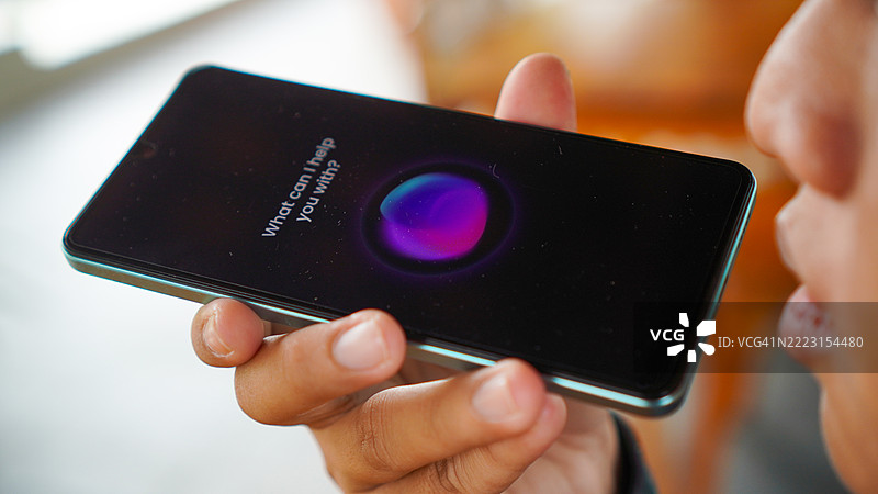 亚洲年轻男子在智能手机上使用语音助手图片素材