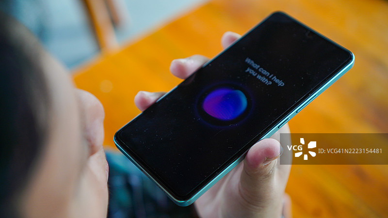 亚洲年轻男子在智能手机上使用语音助手图片素材