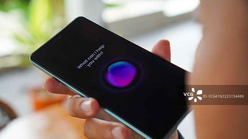 亚洲年轻男子在智能手机上使用语音助手图片素材