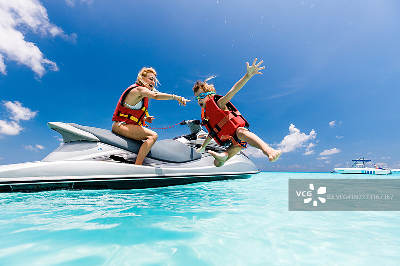 快乐的单身母亲和儿子在海上乘坐喷射船享受乐趣。图片素材