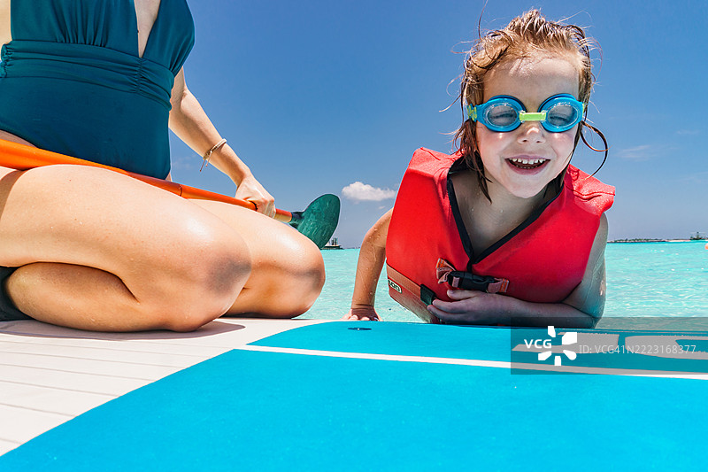 快乐的男孩和他的单身母亲在海上划桨板享受时光。图片素材