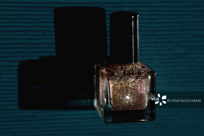 金色闪光指甲油与蓝色陶瓷背景相映衬图片素材
