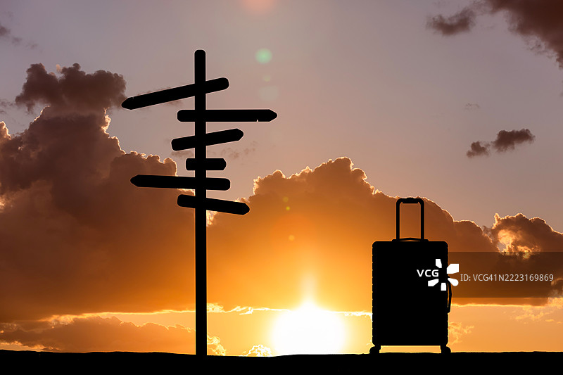日落时的指示牌和行李箱。旅行概念图片素材