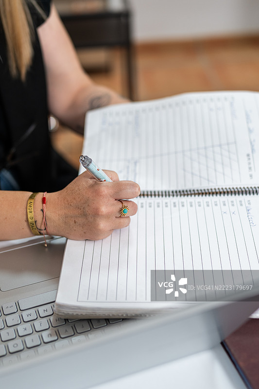 发型师正在用笔记本电脑在日程表上做笔记图片素材