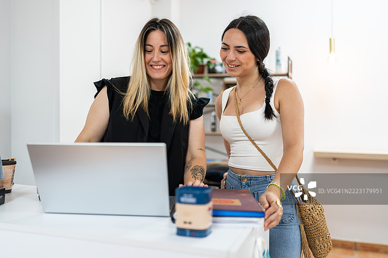 发型师向顾客展示笔记本电脑上的预约日程表图片素材