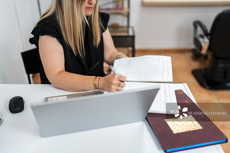 发型师在发廊管理预约并使用笔记本电脑工作图片素材