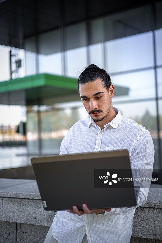 年轻企业家在城市公园里使用笔记本电脑远程工作。数字游牧生活方式在户外。图片素材