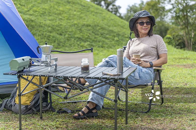 快乐的亚洲女性在大自然中露营时享受咖啡图片素材