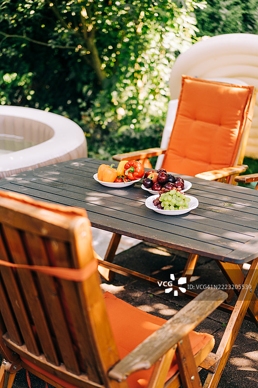 阳光明媚的花园中，户外露台桌上摆满了新鲜的水果和蔬菜图片素材