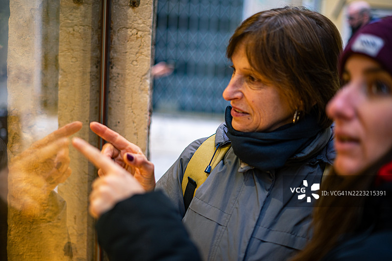 游客通过玻璃窗观察意大利的历史细节图片素材