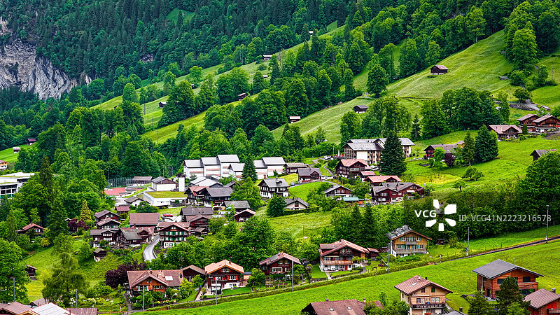 劳特布伦嫩村的鸟瞰图,传统瑞士小木屋和木房子坐落在绿色的阿尔卑斯山谷中,四周被森林覆盖的山脉和壮观的悬崖环绕,适合旅行和建筑用途的风景文化景观。图片素材