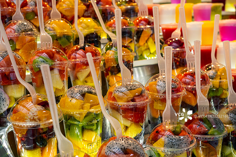 新鲜水果沙拉装在塑料杯中，配有叉子，随时可以享用图片素材