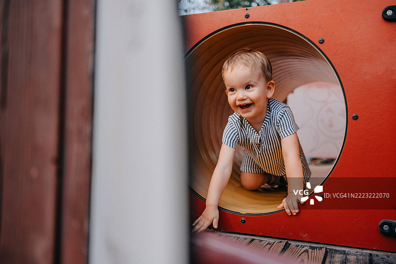 一个小孩正在游乐场的隧道里爬行图片素材